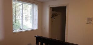 Um quarto com janela, porta para um armário e termostato na parede.