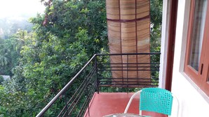 A balcony with a metal railing, a glass table, and a turquoise chair. - Nature Villa 107 Kandy - Hostel (Kandy)
