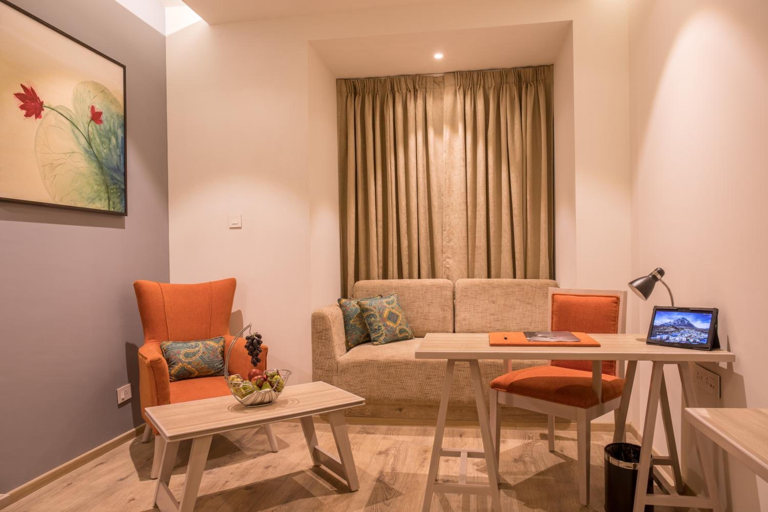 Una sala de estar moderna con un sofá, sillones, una mesa de centro, un escritorio con una computadora portátil y un cuadro en la pared.