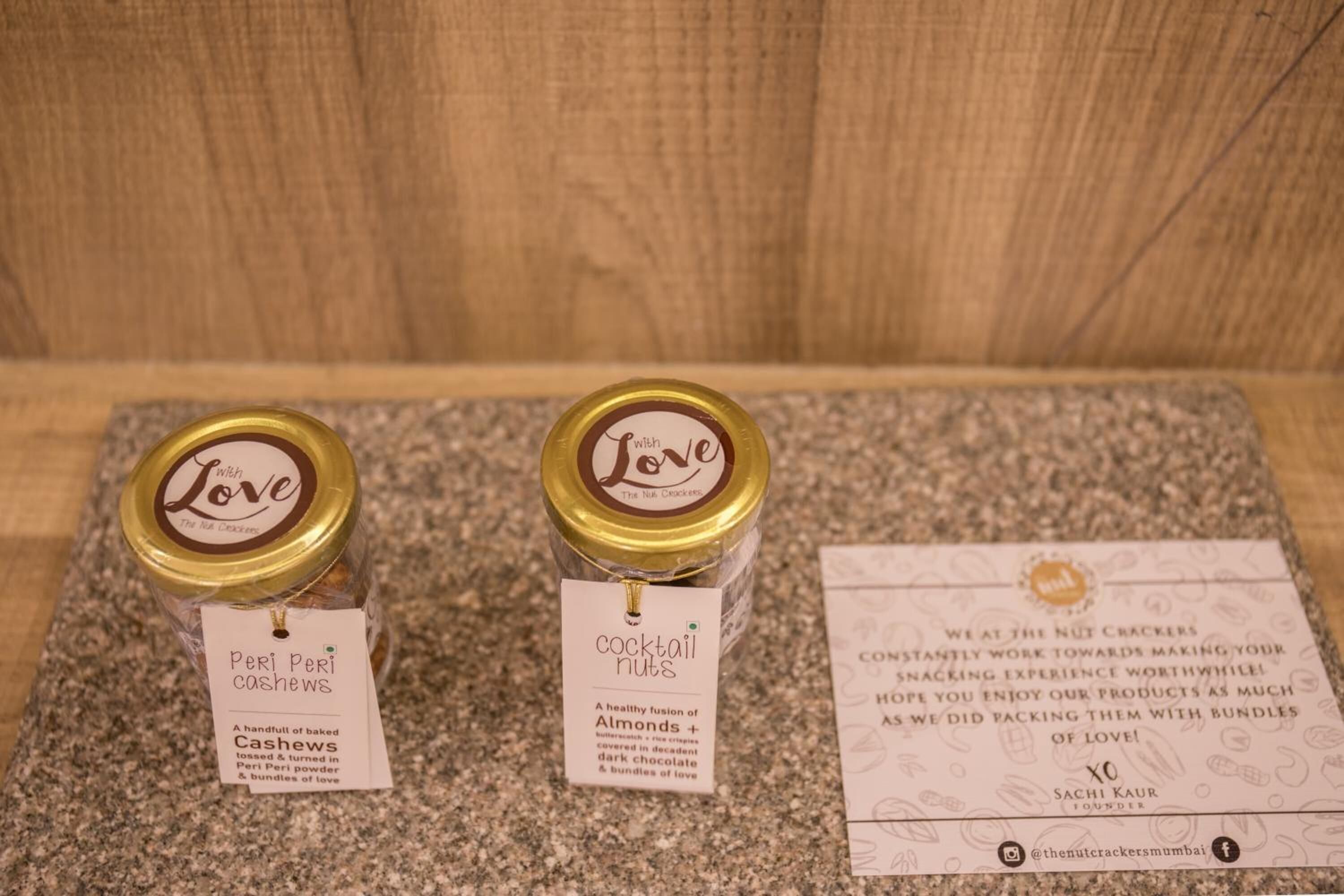 Two jars labeled 'Peri Peri Cashews' and 'Cocktail Nuts' with descriptions and a business card.