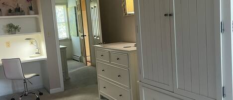 A bedroom with a desk, a large wardrobe, and a staircase leading to another room.