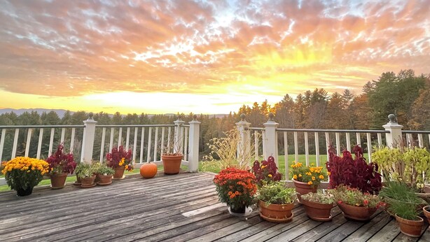 A wooden deck with potted plants and a white fence. - High Hill Inn (East Montpelier)
