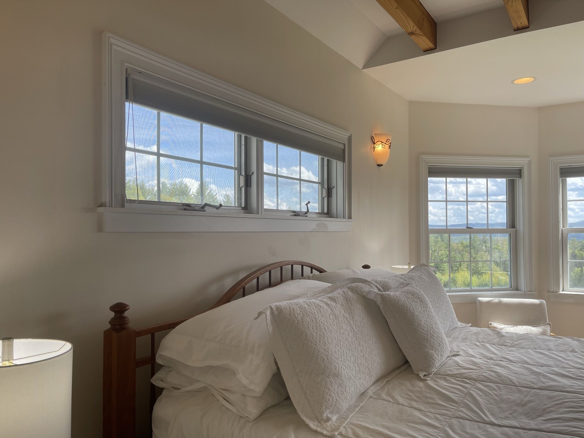 Une chambre à coucher avec un lit, deux fenêtres et un luminaire fixé au mur.