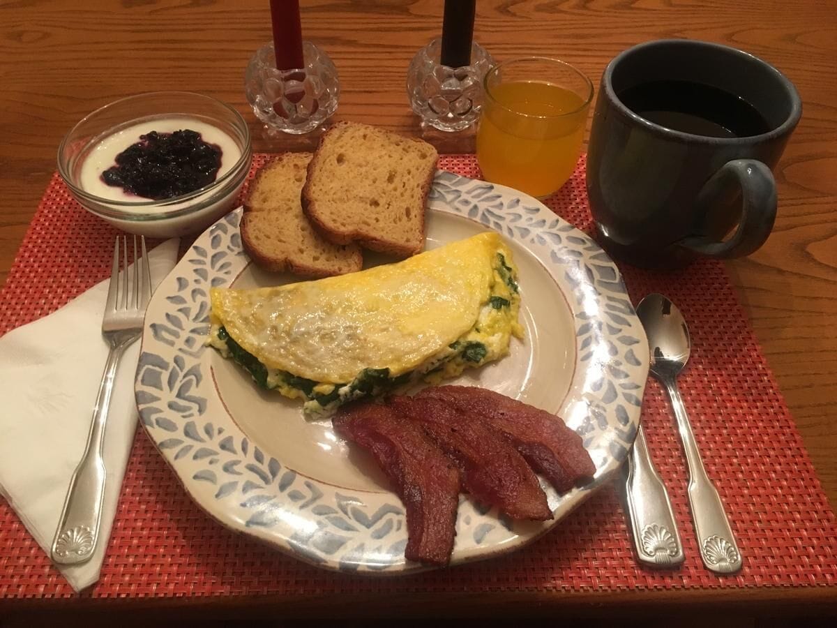 A breakfast plate with eggs, bacon, toast, and jam.