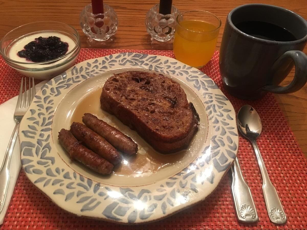 Un plato con pan, salchichas y un bol de compota de frutas.
