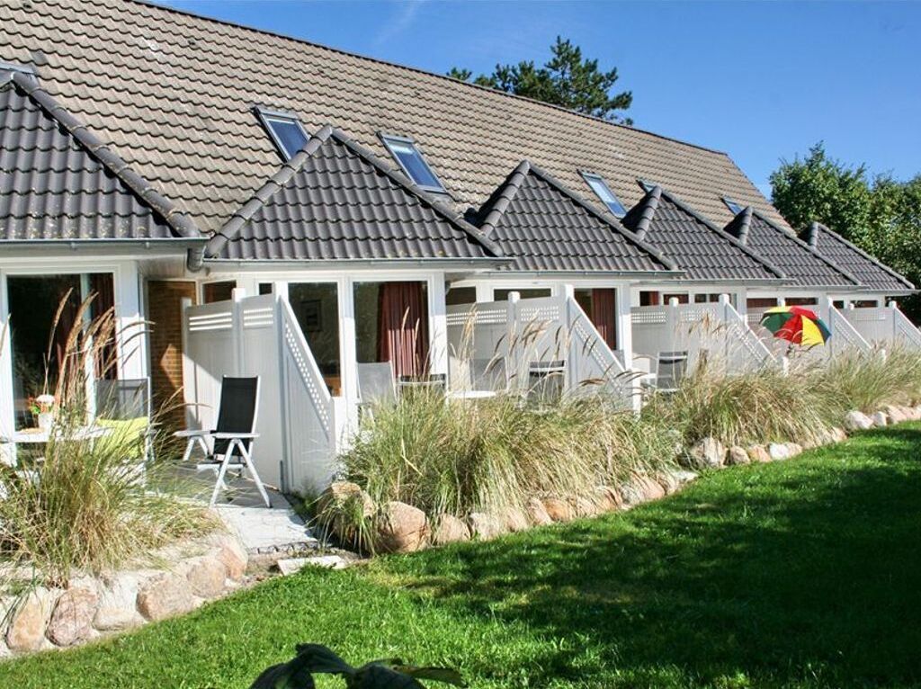 A row of houses with sloped roofs and skylights, a grassy lawn, and a small pool area.