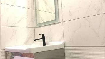 Un baño con un lavamanos blanco, un espejo y un inodoro.