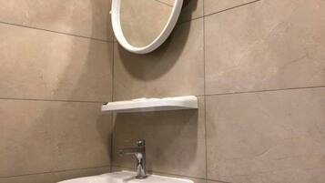 Un baño con lavamanos blanco, espejo e inodoro.