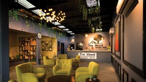 A lobby with green armchairs, a reception desk, and a clock on the wall. - The Wood Boutique Hotel (Muar)