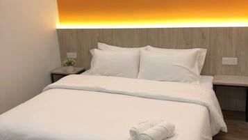 Une chambre d’hôtel équipée d’un lit, d’une table de chevet, d’un appareil de climatisation et d’un mur agrémenté d’une bande lumineuse à lumière chaude.