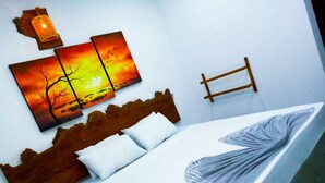 Ein Bett mit weißer Matratze und grauer Decke, einem hölzernen Kopfteil und einem an der Wand befestigten Bettrahmen aus Holz.