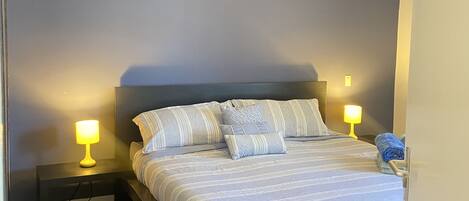 A bedroom with a bed, two bedside lamps, a ceiling fan, and a nightstand.