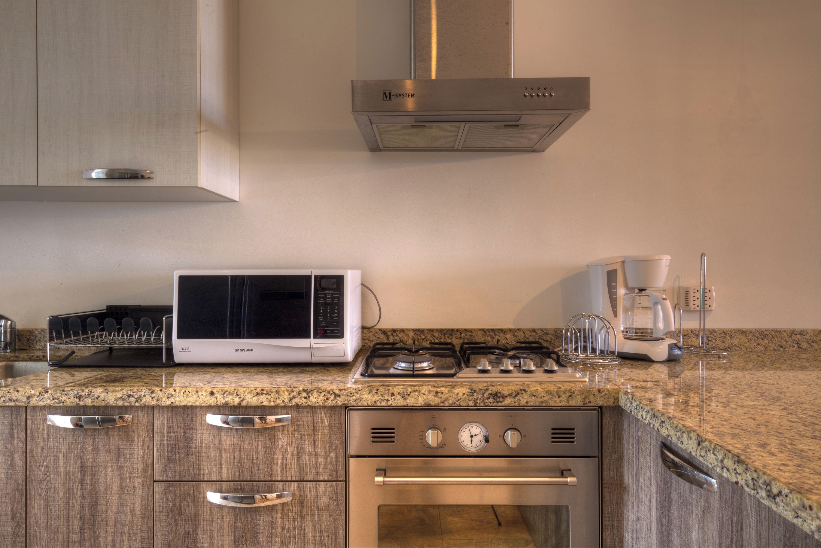 Una cucina accessoriata con forno a microonde, fornelli, forno e macchina da caffè.