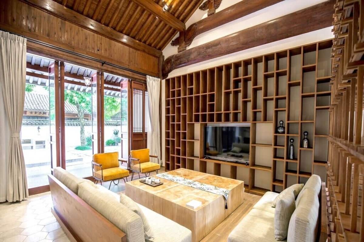 Uma sala de estar em estilo tradicional, com um sofá, uma mesa de centro e uma televisão fixada em uma parede de madeira.