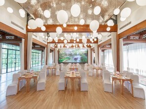 A conference room with a long table, white chairs, and a large screen at the front.