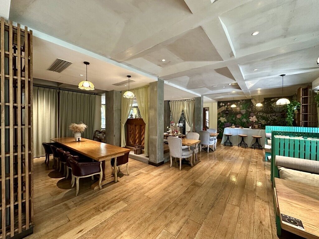 A spacious dining area with a wooden table and chairs, a green sofa, and a decorative wall with plants.