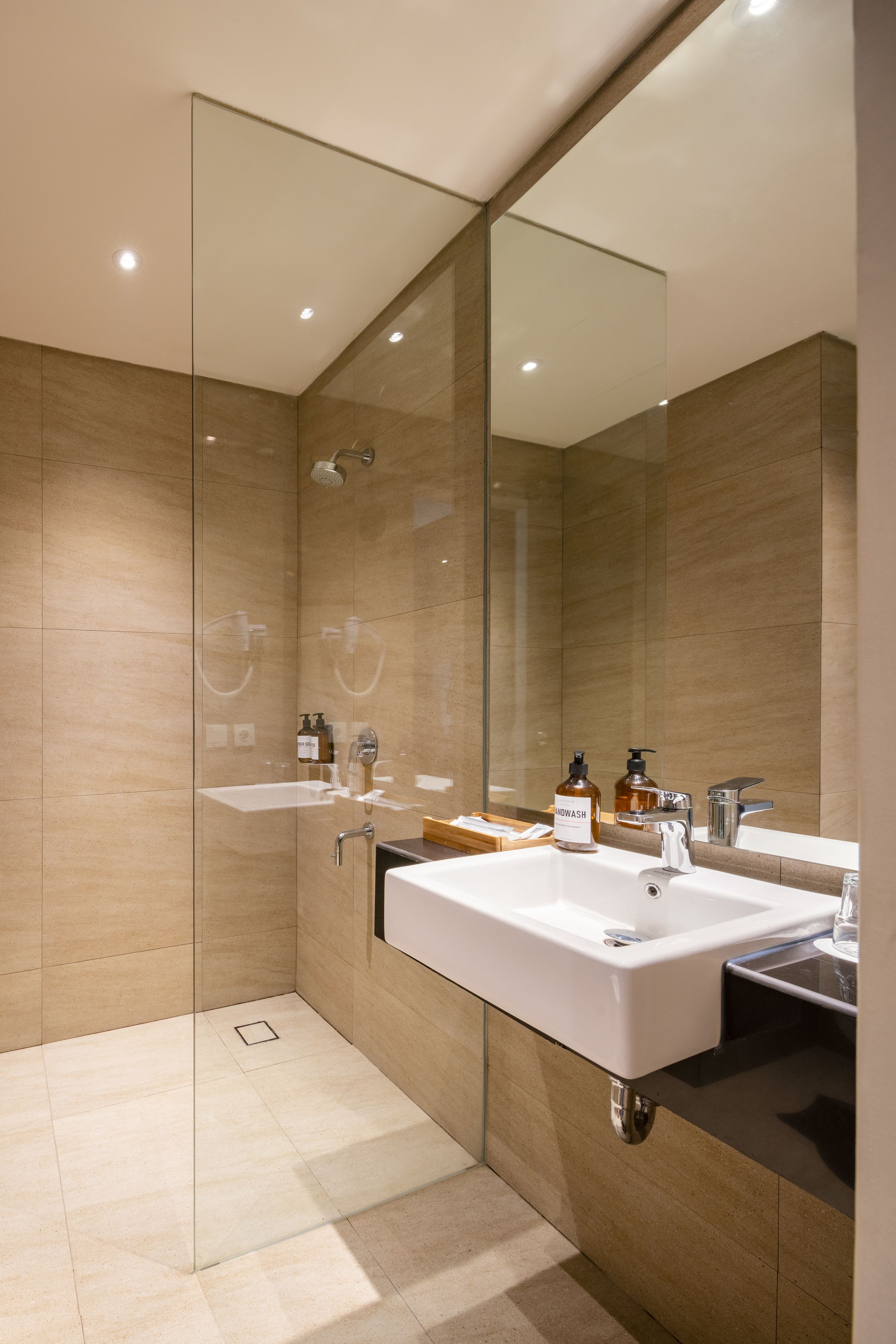 A modern bathroom with two sinks, a large mirror, and a shower area.