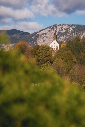 A church with a bell tower, surrounded by trees and mountains.