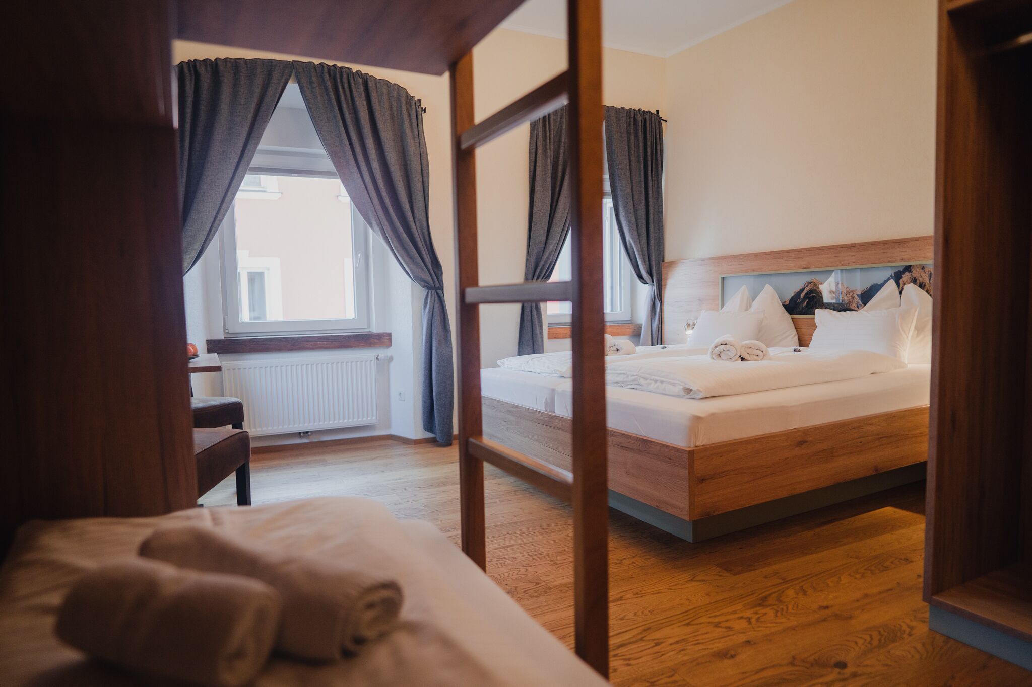 A hotel room with a wooden bed, a desk, and a window with curtains.