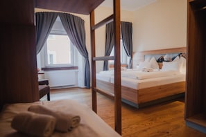 A hotel room with a wooden bed, a desk, and a window with curtains.