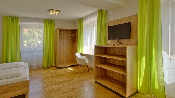 A room with a bed, a desk, a chair, a TV, and a wardrobe.