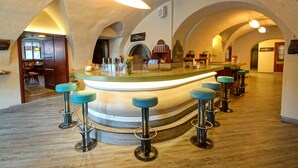 Zona de bar con una barra curva, varios taburetes y un techo abovedado cálido.