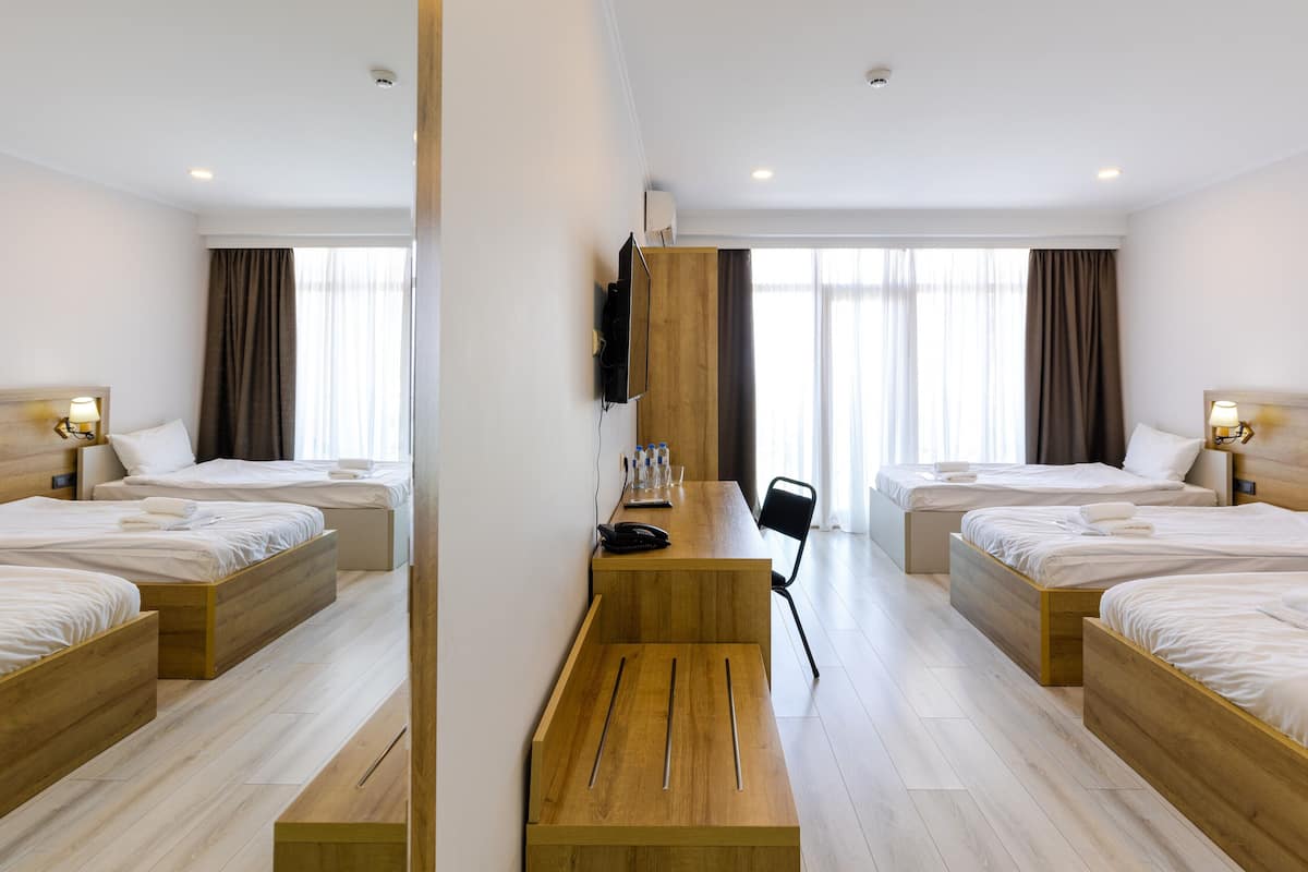 Ett hotellrum med två sängar, ett skrivbord i trä, en platt-TV och ett stort fönster med gardiner.