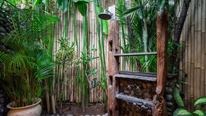 A bamboo shower enclosure with a stone wall and a wooden shelf. - Luxury Enclosed Villa CHARM in Seminyak - 3 min walk to the beach (Seminyak)