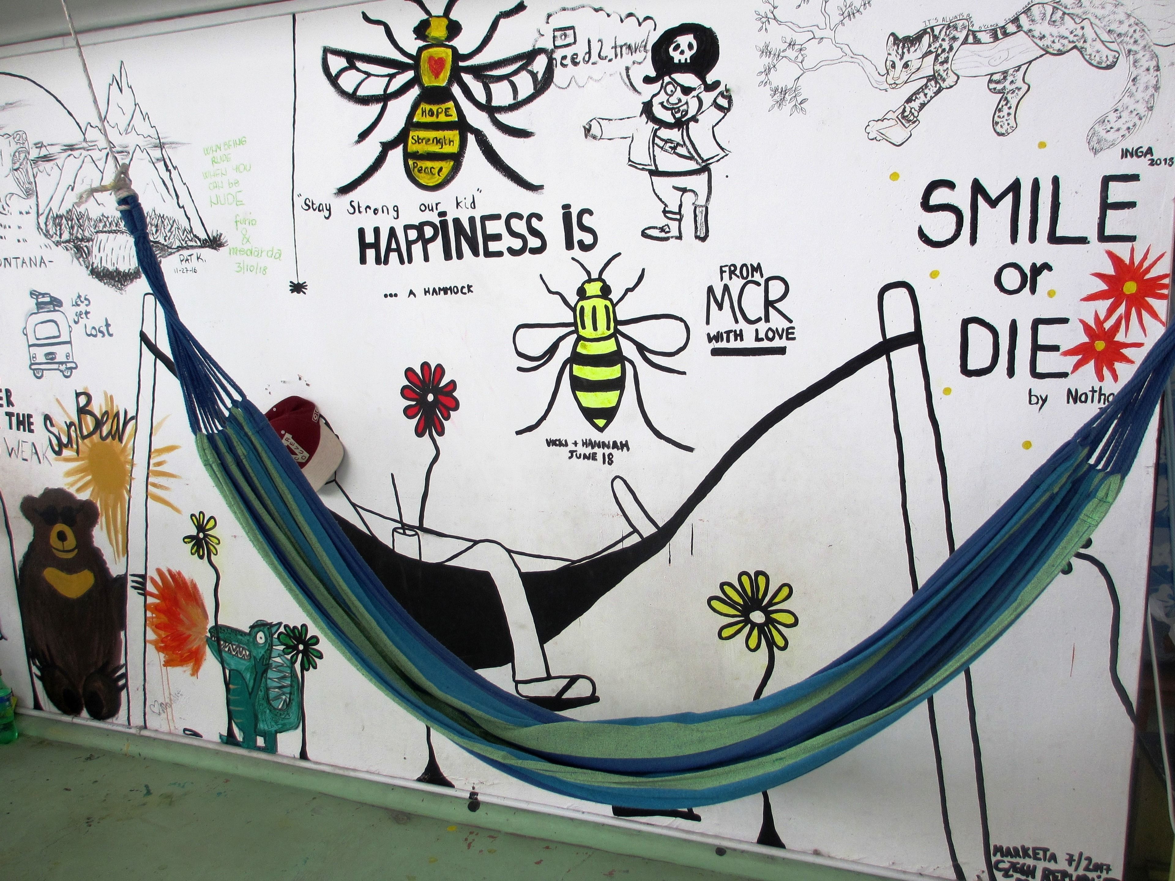 Pared con diversos dibujos y texto, incluyendo una hamaca, un oso y una abeja.