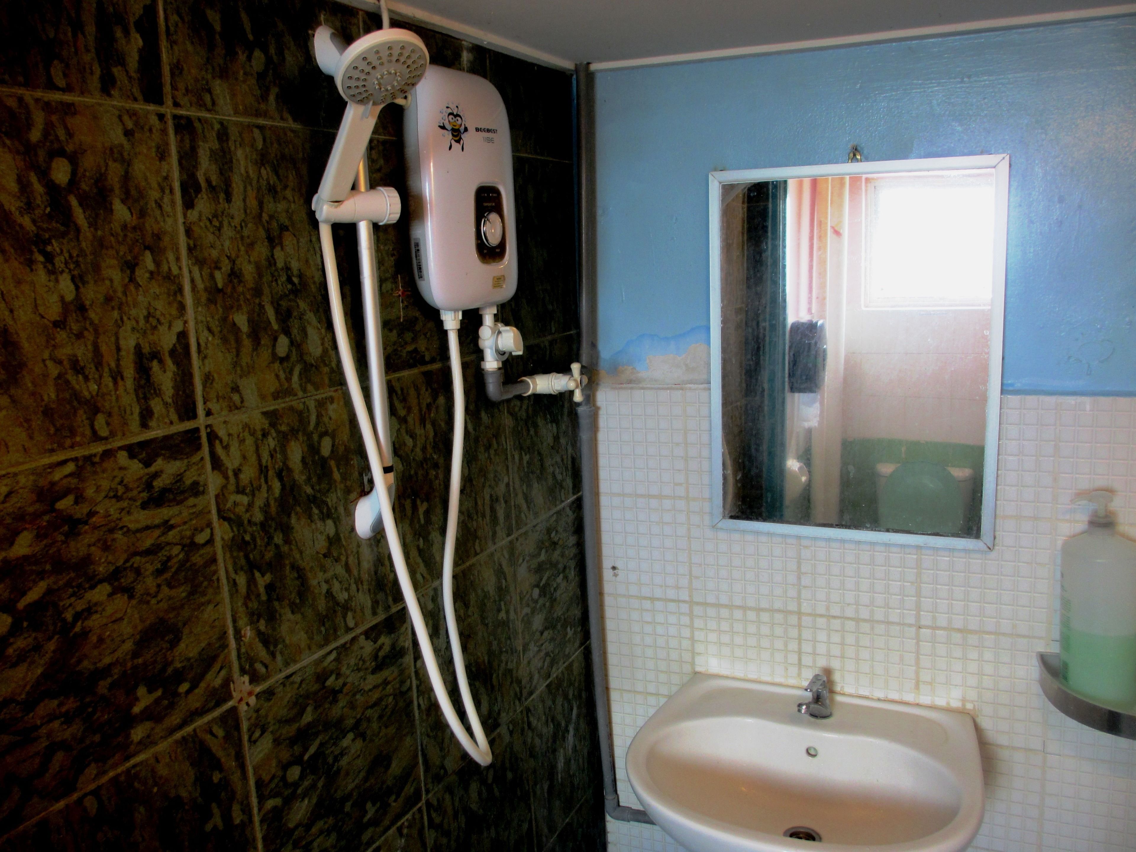 Un baño con ducha, lavamanos y espejo.