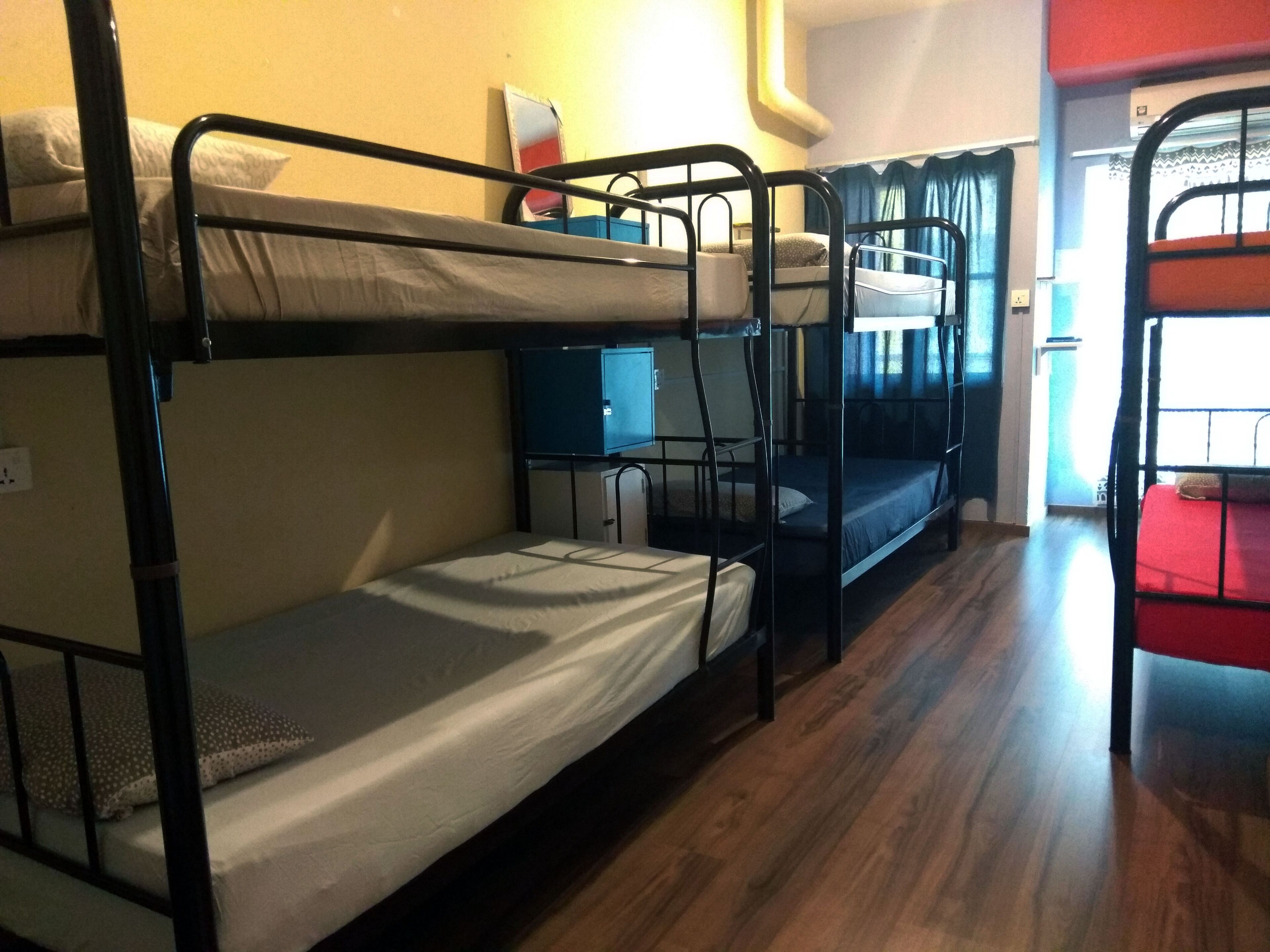 A dormitory room with bunk beds, a desk, and a red couch.