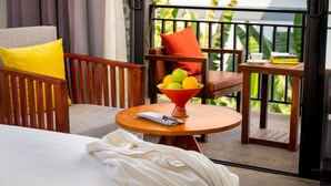 A balcony with a wooden table, a bowl of fruit, a chair, and a sofa with cushions. - Silver Smith Residence (Siem Reap)
