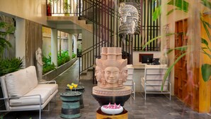 A modern lobby with a sofa, a decorative sculpture, and a staircase. - Silver Smith Residence (Siem Reap)