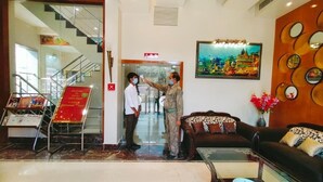 A hotel lobby with a staircase, a reception desk, a sofa, and a painting on the wall. - Hotel Ozas Grand (Varanasi)