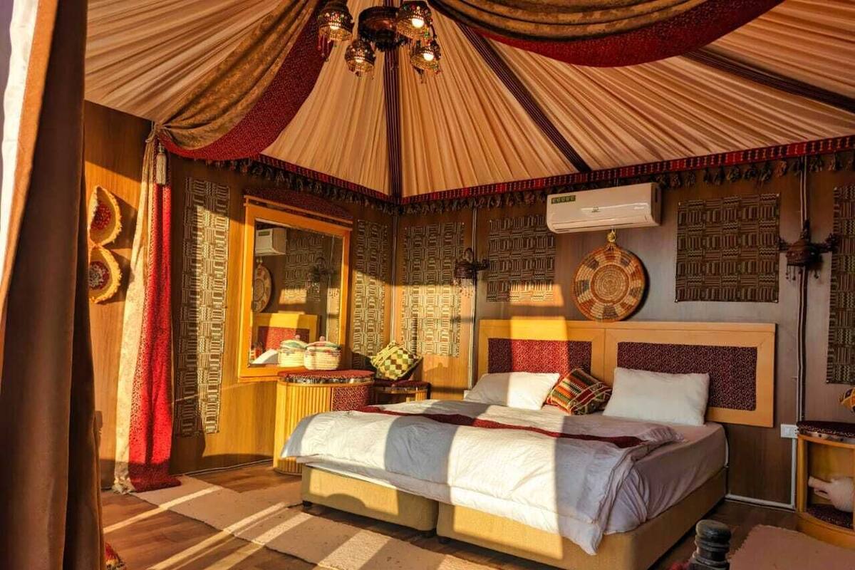 Une chambre avec un grand lit, un miroir, des décorations murales à motifs et un ventilateur de plafond.