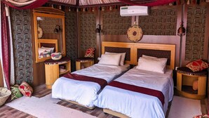 A room with two beds, patterned walls, a mirror, and decorative pillows. - Desert Sand Camp (Wadi Rum)