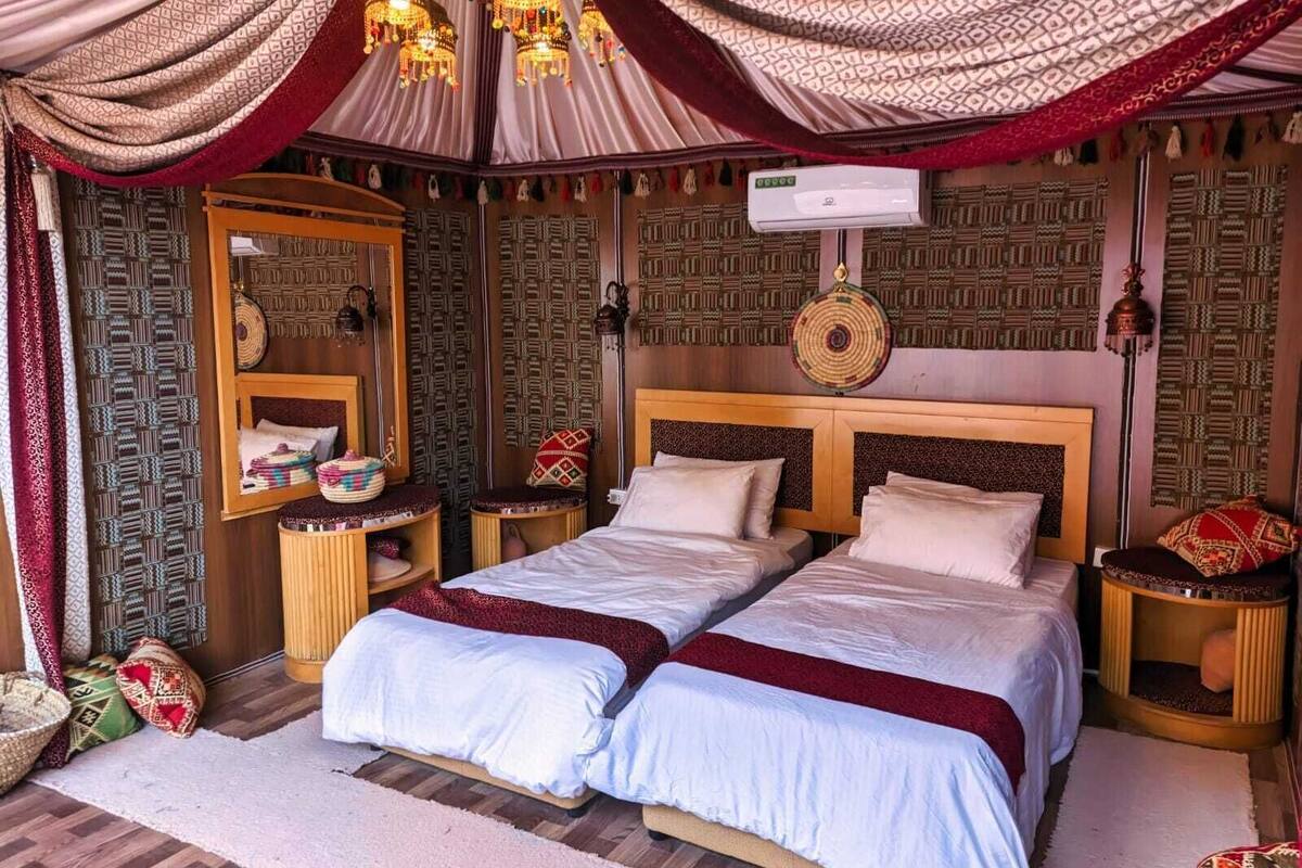 Une chambre avec deux lits, des murs à motifs, un miroir et des coussins décoratifs.
