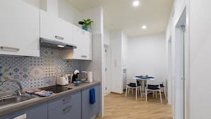 A compact kitchen with a tiled backsplash, a built-in oven, and a dining area with a table and chairs. - VIAPARSANO - two bedrooms flat (Sorrento)