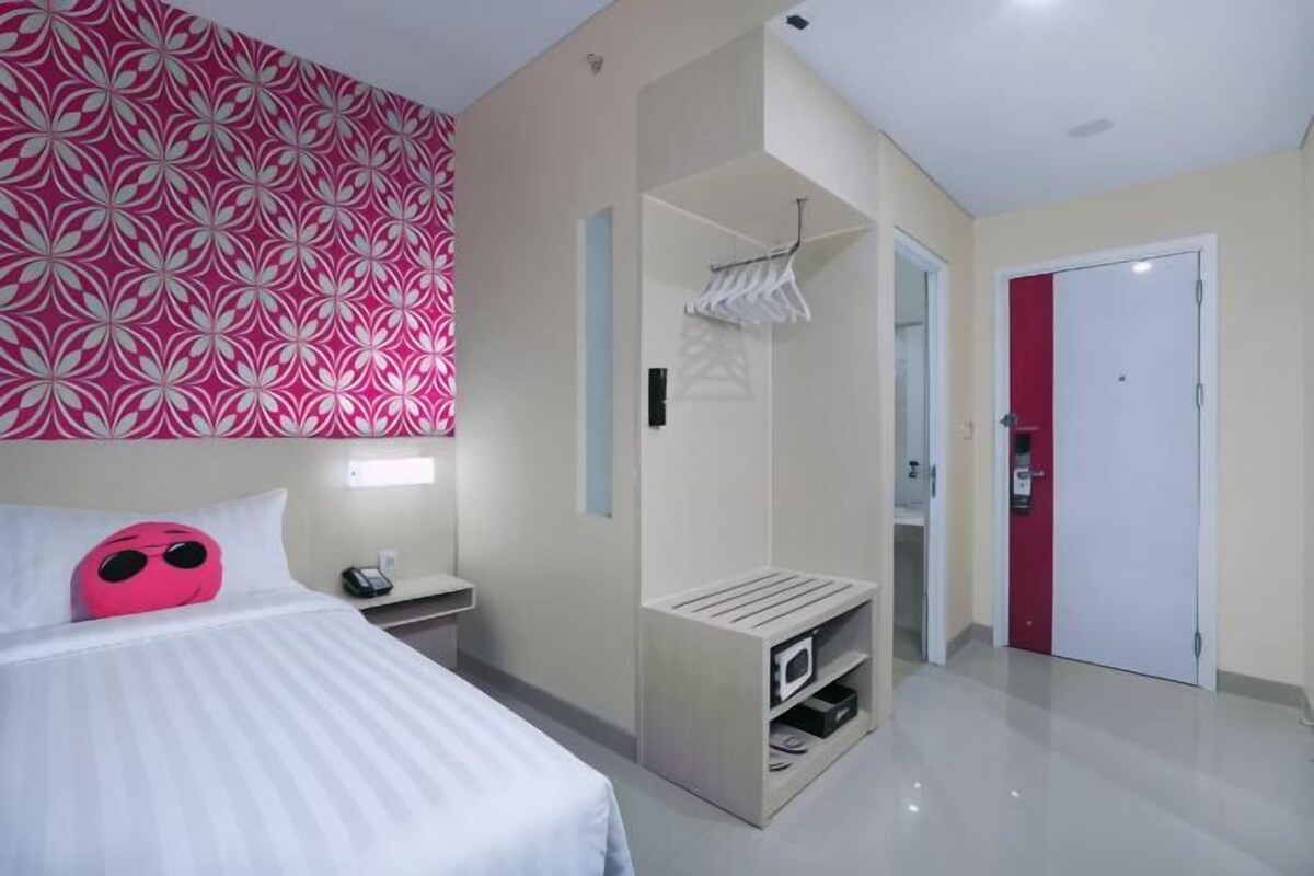 A hotel room with a bed, a wardrobe, a mirror, and a door.