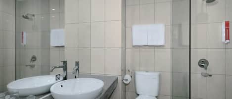 A modern bathroom with two sinks, a toilet, and a glass-enclosed shower.