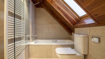 A bathroom with a bathtub, toilet, and a skylight.