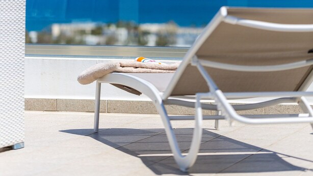 A lounge chair with a towel on it, overlooking a clear blue sky and a distant view of the sea. - 3-bedroom villa close to the beach at Triton SeaView Villas with common poolS (Asprouliani)