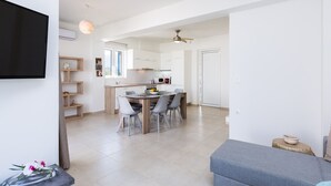 A modern kitchen with white cabinets, a dining table with chairs, and a ceiling fan. - 3-bedroom villa close to the beach at Triton SeaView Villas with common poolS (Asprouliani)