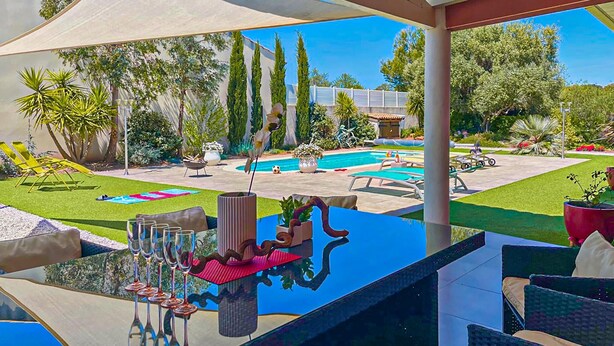 A poolside area with a glass table, lounge chairs, and a view of a swimming pool and garden. - Gorgeous home in Creissan (Creissan)