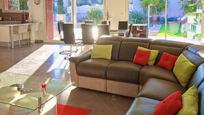 A modern living room with a sectional sofa, a glass coffee table, and a dining area with a kitchen in the background. - Gorgeous home in Creissan (Creissan)