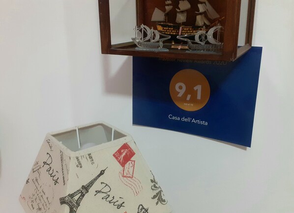 A framed award plaque for 'Casa dell'Artista' with a score of 9.1 out of 10, and a decorative item resembling a Parisian mailbox with 'Paris' and '5' stamps.