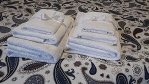 Dos montones de toallas blancas con lazos, sobre una alfombra estampada.