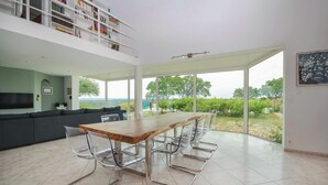 Ein moderner Essbereich mit einem Holztisch, Metallstühlen, einem grauen Sofa und Blick ins Freie.