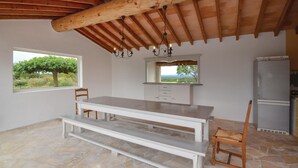 Eine geräumige Küche mit Steinboden, Holzbalkendecke, großem Fenster mit Ausblick und integriertem Kühlschrank.