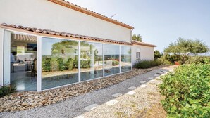 Ein modernes Haus mit großen Glasfenstern, einem Ziegeldach und einem Schotterweg.